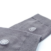 Detailfoto van de grijze bamboe sokken afgewerkt met het witte  geborduurd logo